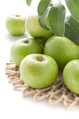 Juicy green apples on a white table with wicker stand