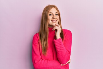 Young irish woman wearing casual clothes smiling looking confident at the camera with crossed arms and hand on chin. thinking positive.