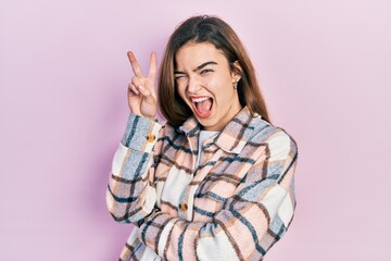 Young caucasian girl wearing casual clothes smiling with happy face winking at the camera doing victory sign with fingers. number two.