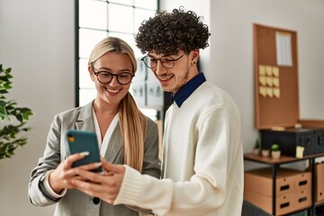 Two business executives smiling happy using smartphone at the office.