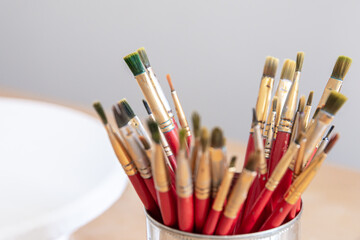 Close-up of red paint brushes in a metal jar.