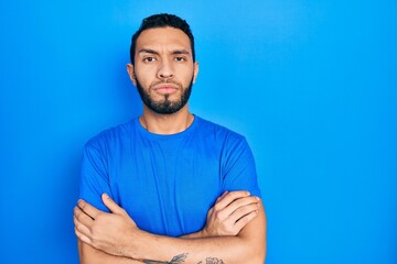 Hispanic man with beard wearing casual blue t shirt skeptic and nervous, disapproving expression on...