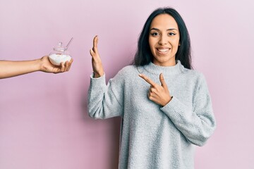 Young hispanic girl rejecting bowl with sugar smiling happy pointing with hand and finger
