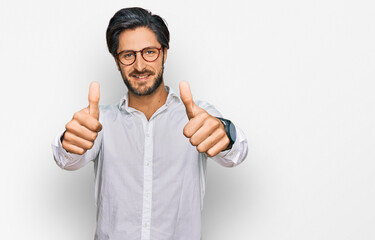 Young hispanic man wearing business shirt and glasses approving doing positive gesture with hand,...