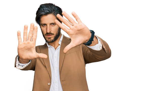 Young hispanic man wearing business clothes doing frame using hands palms and fingers, camera perspective