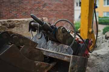 Close-up shot of the pneumatic jackhammer and buckets for the excavator lying on the ground at the demolition site.