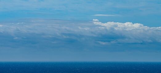 Naklejka na ściany i meble Panoramic view of bright blue sea, blue sky with fluffy white clouds