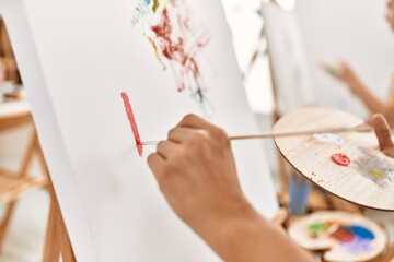 Two hispanic paint students at art studio. Man painting on canvas using paintbrush.