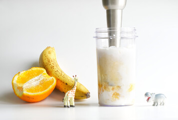 Making a baby milk shake or a banana and orange smoothie. Using a hand blender. Concept picture for...