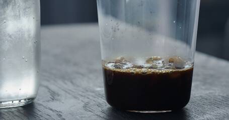 making espresso tonic, add crushed ice in tumbler glass and pour espresso on black wood table