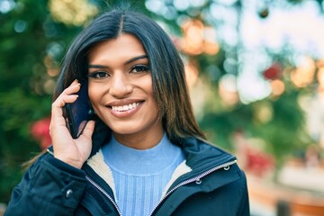 Young hispanic woman speaking on the phone outdoor by christmas decorations