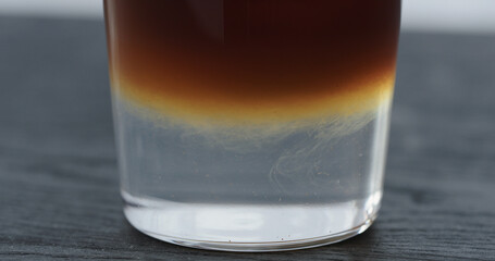 espresso tonic in tumbler glass on black wood table closeup
