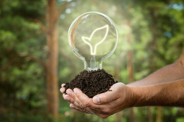 Hands holding soil with light bulb. Sustainable and eco friendly energy sources. Earth energy concept.