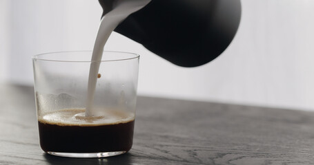 making cappuccino in tumbler glass on black aok table