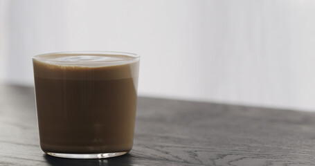 cappuccino in tumbler glass on black aok table