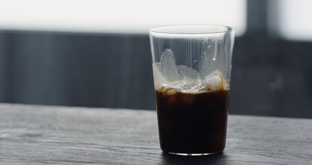 making espresso tonic, pour espresso over ice on black wood table