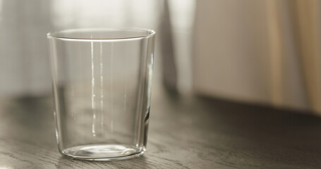 empty tumbler glass on black oak table