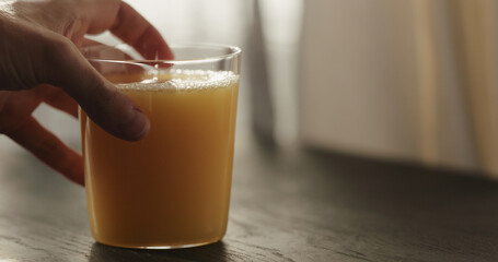 man hand take orange juice in tumbler glass from black wood table with copy space
