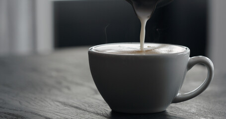 pour steamed milk into white cup making cappuccino with copy space