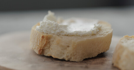 cream cheese on fresh baguette slice on olive board closeup