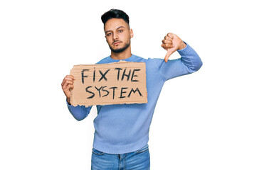 Young arab man holding fix the system banner cardboard with angry face, negative sign showing...