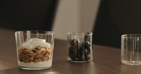 make granola with yogurt in tumbler glass on walnut table