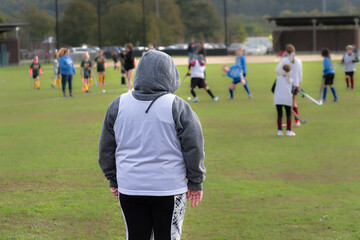 Fototapeta premium The goalie is all bundled up on this very chilly October day. Girls field hockey on a cold Autumn afternoon.