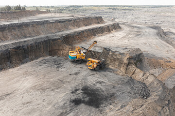 Panoramic aerial view of coal mine. Open pit mine industry, big yellow mining truck for coal quarry. Open coal mining anthracite mining. Pit on coal mining by open way. Rock loading in trucks
