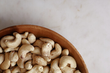 Tasty cashew nuts in bowl on a wooden table, top view. Space for text