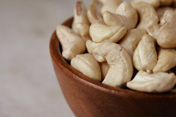 Tasty cashew nuts in bowl on marble table, side view. Space for text
