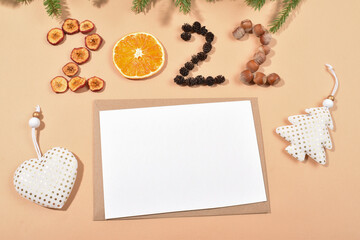 An envelope and a blank sheet on a beige background with the numbers 2022 made of natural materials.
