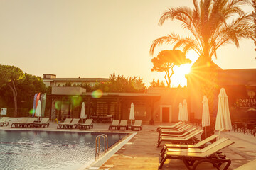 swimming pool and sun beds in the luxury hotel in the evening at sunset