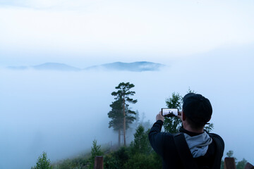 thick fog and a gloomy morning in the forest on a mobile phone camera. a tourist traveler takes pictures of nature on a smartphone camera. a middle-aged man is a lover of hiking, social networks