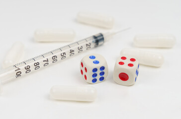 On a white background syringe, pills and dice.