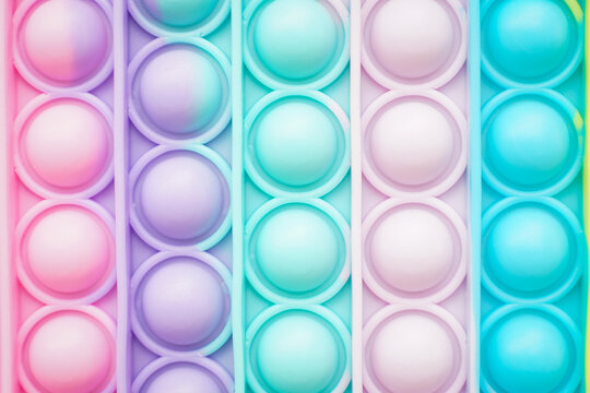 Pop it fidget. Colorful toy push pop it. Close up of anti stress sensory fidget. Trendy popular silicone colorful anti stress pop it toy . 
