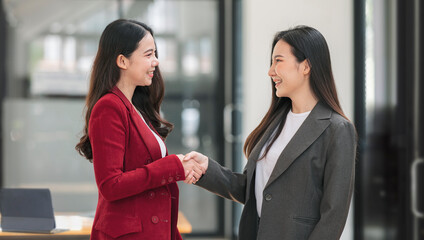 Obraz premium Two Businesswomen Shaking Hands In Modern Office