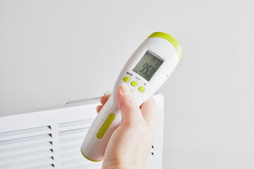 electric infrared thermometer for measuring surface temperature and air on the background of the electric radiator,