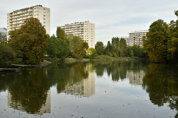 Tours H.L.M. émergeant de la végétation et se reflétant dans l'étang des Pêcheries au parc de la Héronnière à Auderghem 