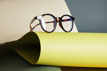 glasses on rolled paper, geometric background, green colors