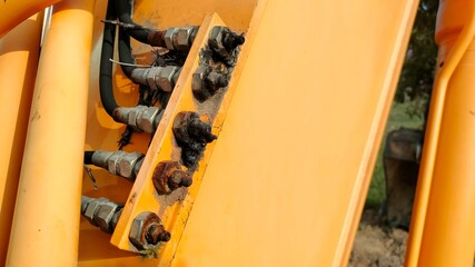 Dirty grease filling head. Row of metal grease fillers on yellow excavator arms. selective focus