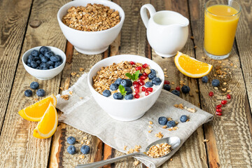 Healthy lifestyle in a breakfast plate with muesli and a spoon on the background of a brown wooden table with milk, berries and orange juice. organic muesli, morning diet for health concept