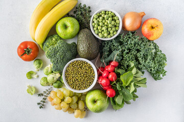 The concept of a healthy vegetarian diet, a selection of fresh products for a detox diet, raw broccoli, apple, spinach, peas, avocado, lime, corn salad, top view. The concept of healthy eating.