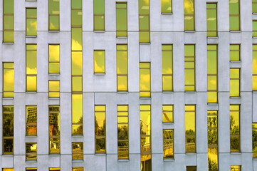 Fragment of office building facade made of yellow toned glass and concrete constructions. Frontal...
