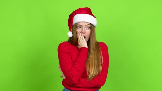 Teenager girl with christmas hat gaping because have just surprised with a gift over isolated background. Green screen chroma key