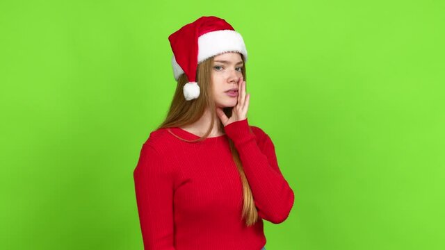Teenager girl with christmas hat shouting to the lateral and announcing something over isolated background. Green screen chroma key