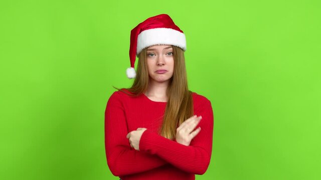 Teenager girl with christmas hat making unimportant and doubts gesture while lifting the shoulders and the palms of the hands over isolated background
