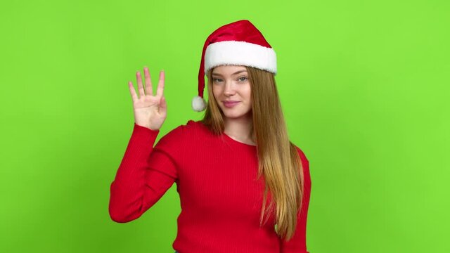 Teenager girl with christmas hat happy and counting with fingers over isolated background. Green screen chroma key