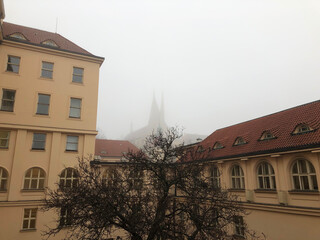 Church towers show through the fog past a monastery