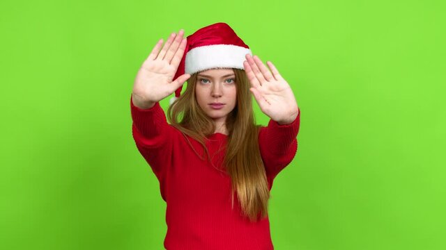 Teenager girl with christmas hat doing stop sign over isolated background. Green screen chroma key