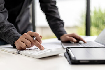 Close-up view A businessman using a calculator to calculate numbers on a company's financial documents, he is analyzing historical financial data to plan how to grow the company. Financial concept.